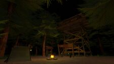 A view of a wooden watchtower with a tent and campfire below on the ground.